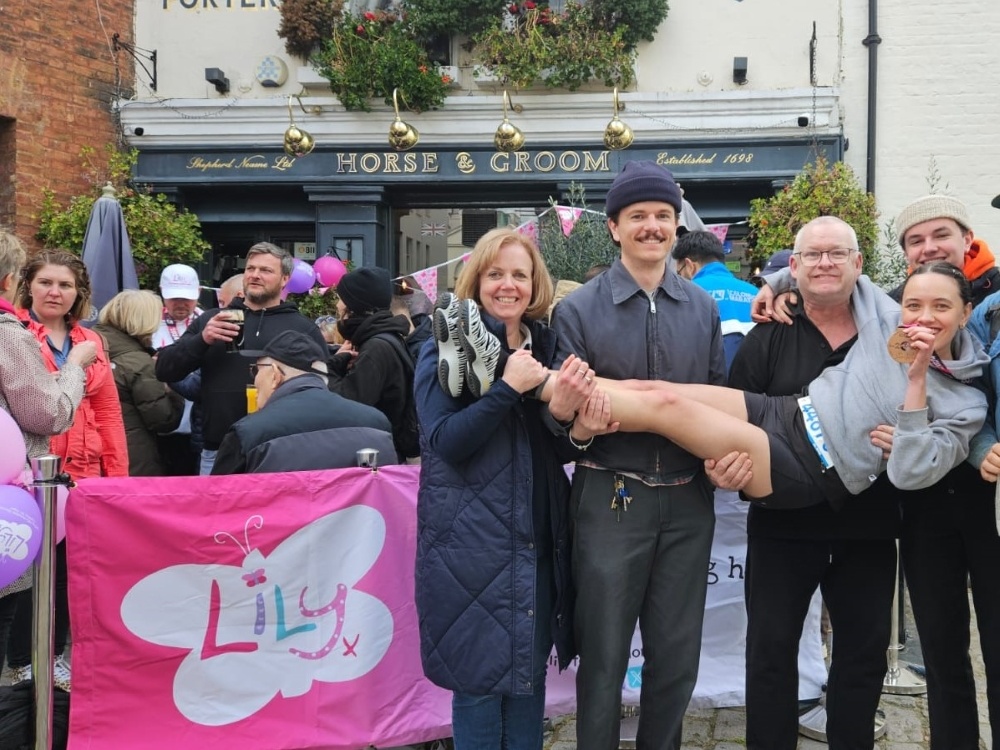 A lady being lifted up by a group of people in front of a Lily Foundation banner