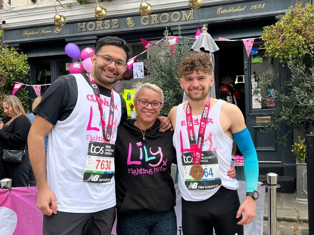 Two runners in Lily vests standing with their arms around a woman
