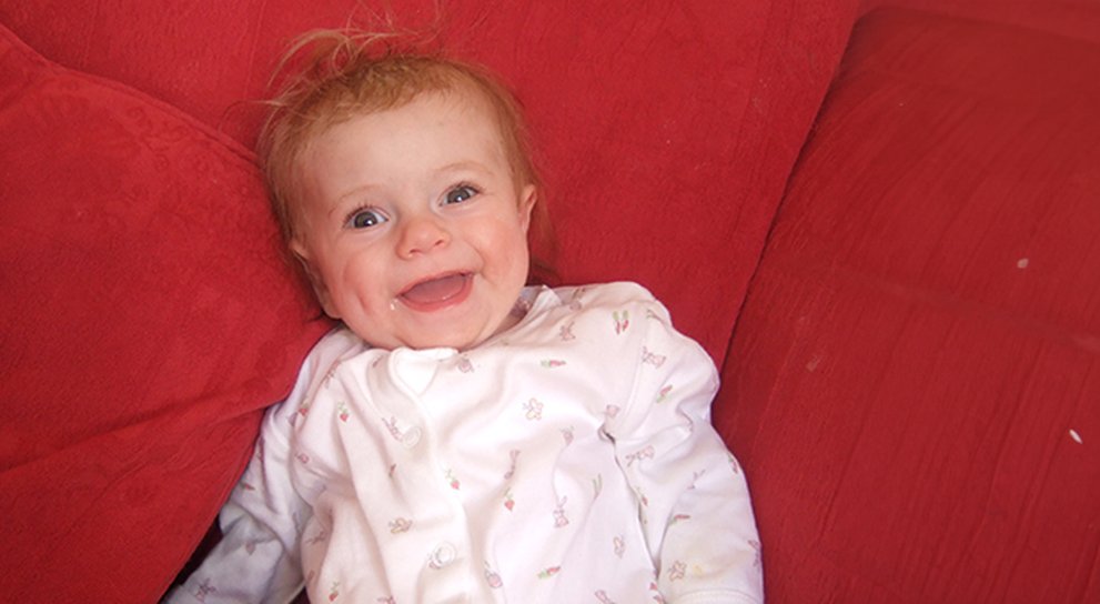 Baby Lily with a big smile on a red blanket