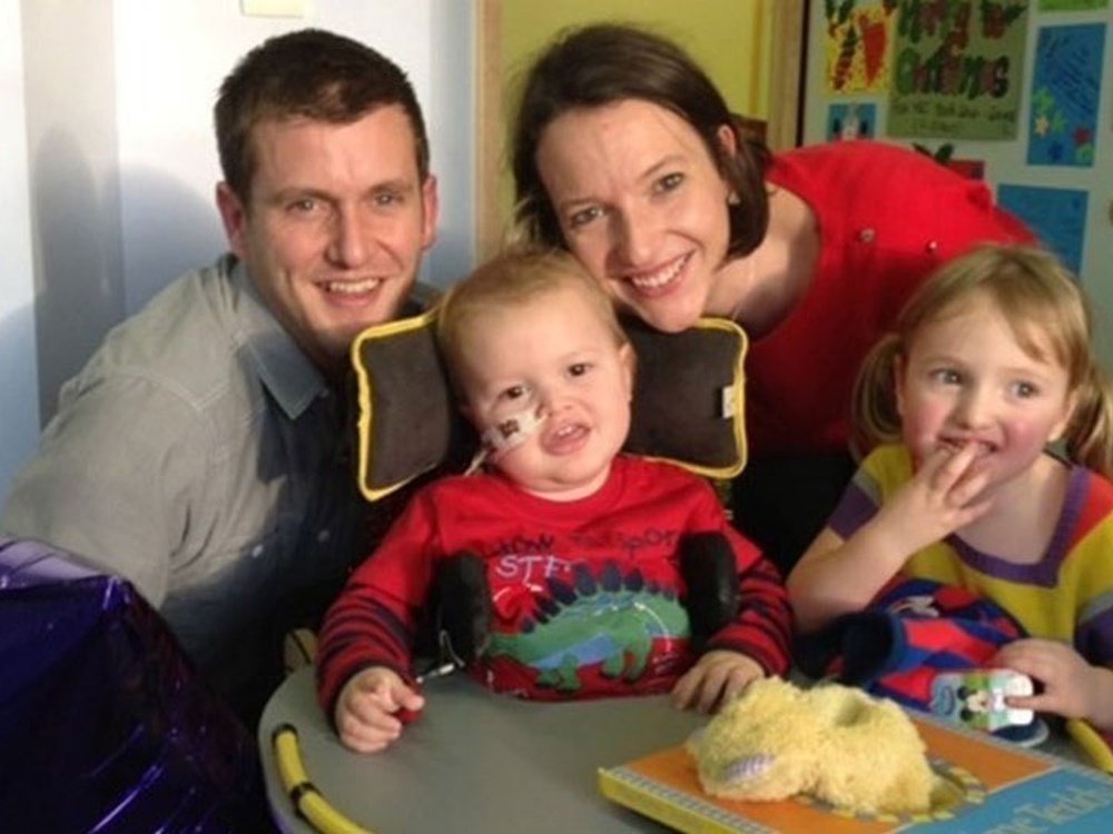 Mum, Dad and two children. Their son has mito and is in a wheelchair with a feeding tube